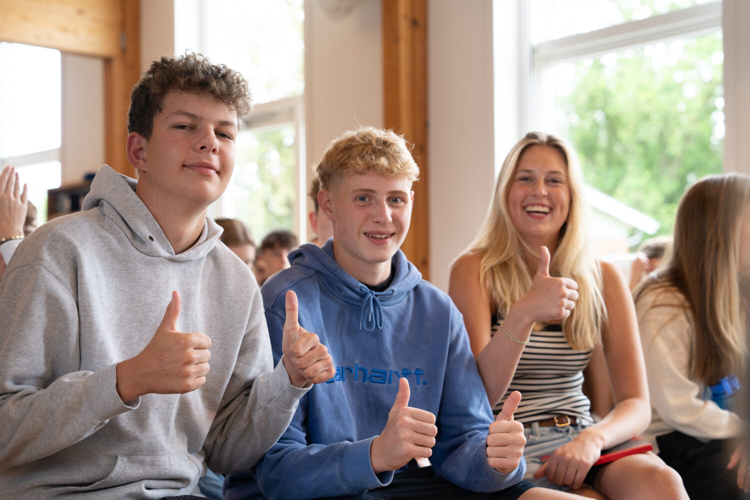 To drenge og en pige giver tømmelfingeren til fotograf, smilenede og glade for at være elever på Flemming Efterskole