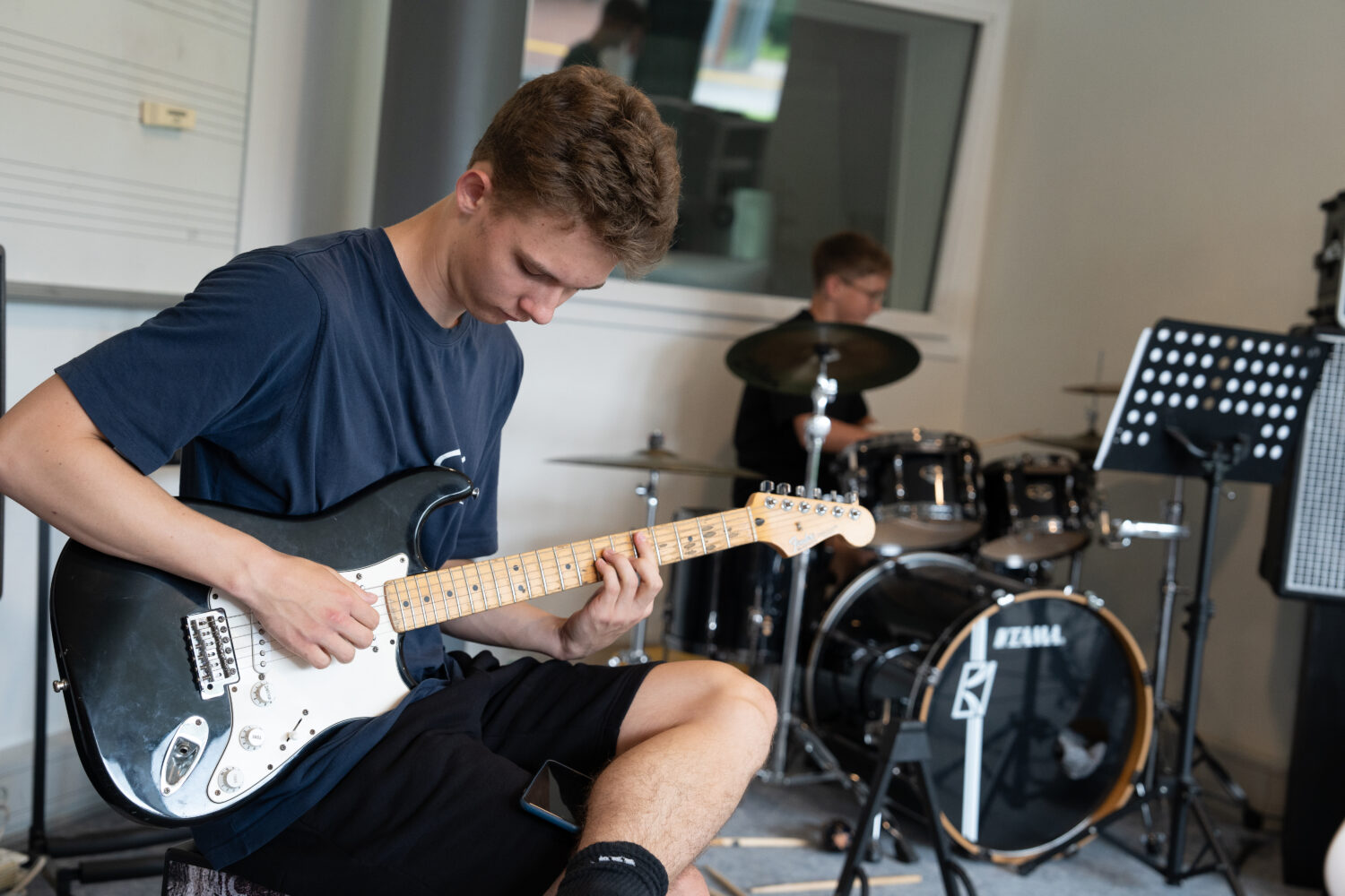 Dreng spiller guitar sammen med bandet i musiklokalet på Flemming Efterskole